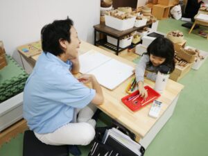 楽しく思考力を育てるどんぐり問題に取り組む子どもと、見守るスタッフ